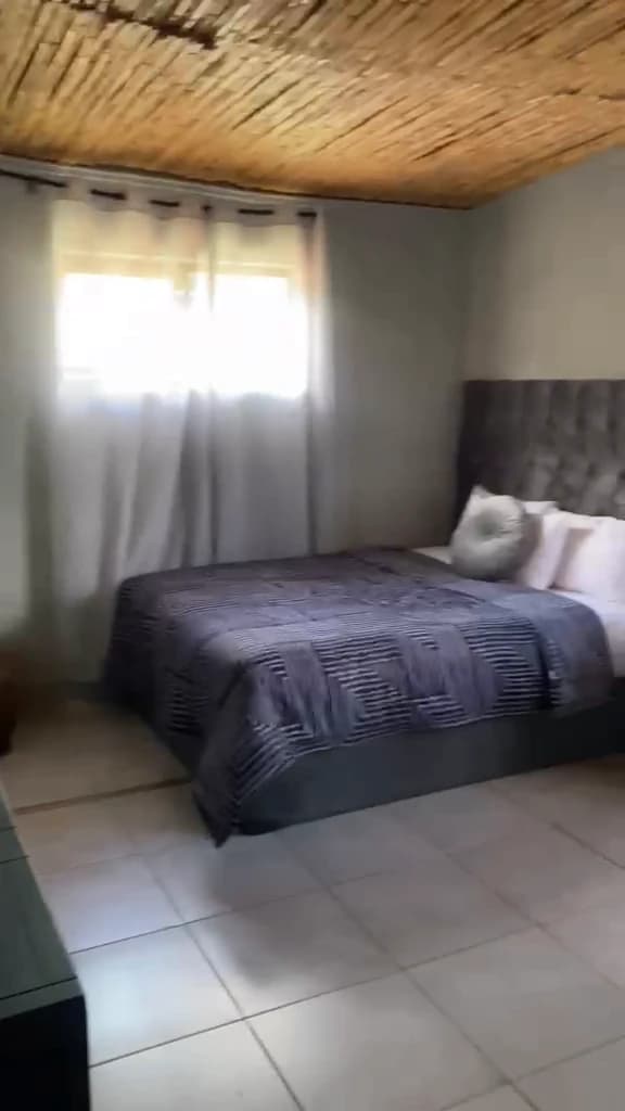 Frame from the guest space video showing a made bed beside a curtained window
